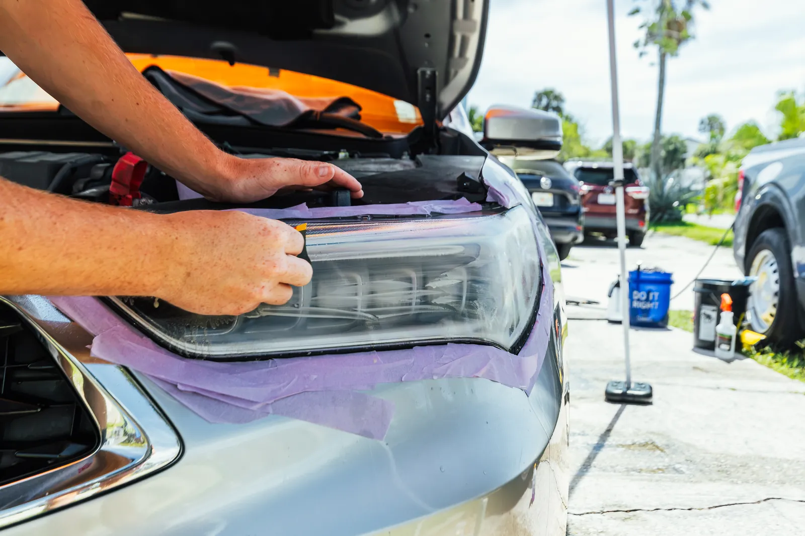 Professional headlight restoration process on a silver Ford